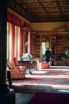 a man standing in the middle of a living room filled with furniture and bookshelves