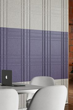 an apple laptop sitting on top of a table in front of a purple and white wall