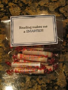 some candy wrapped in plastic on top of a counter with a sign that says reading makes me a smartie