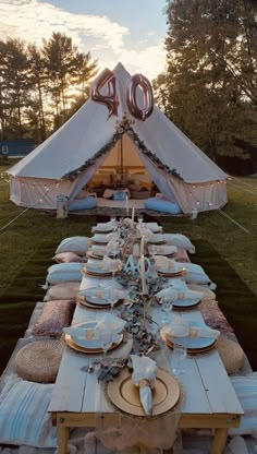 a table set up with plates and place settings in front of a teepee tent