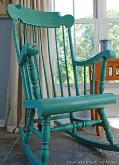 a green rocking chair sitting in front of a window