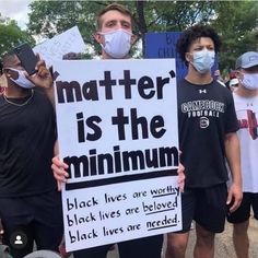 some people are holding signs and wearing masks