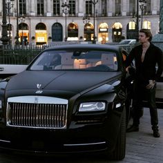 a man standing next to a black car