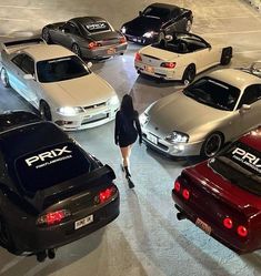 a woman walking through a parking lot next to many parked cars