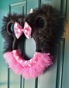 a minnie mouse wreath with pink and white polka dot tutues hanging on a door