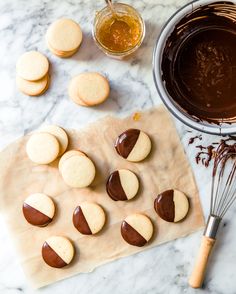 cookies are arranged on a cookie sheet next to a whisk and chocolate sauce