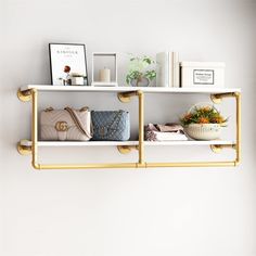 two shelves with purses, books and other items on them against a white wall