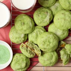 green powdered pastries on a cooling rack next to two cups of white liquid