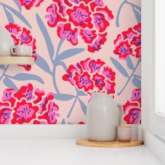 a pink and blue floral wallpaper with two vases on the counter next to it