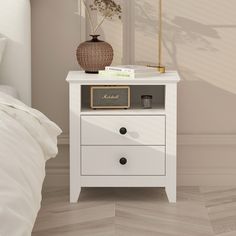 a white bedside table with two drawers and a lamp next to it on top of a bed