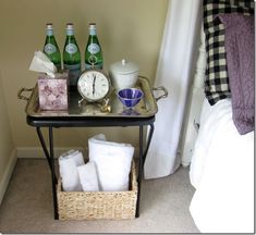 a table with towels, cups and bottles on it next to a bed in a room