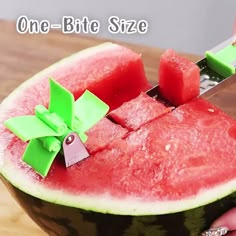 someone cutting into a piece of watermelon with a green knife on top of it