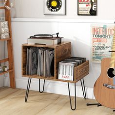 a record player is sitting next to a shelf with records on it and a guitar