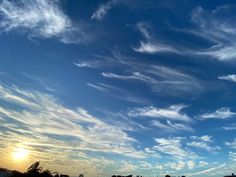 the sky is filled with white clouds as the sun sets in the distance behind it