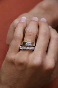 a woman's hand holding an engagement ring with a diamond in the middle and two bands around it