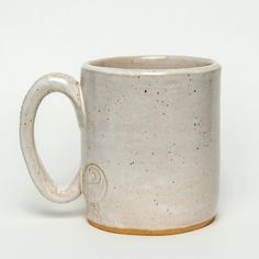 a white coffee mug with brown speckles on the outside and gold rimmed edges