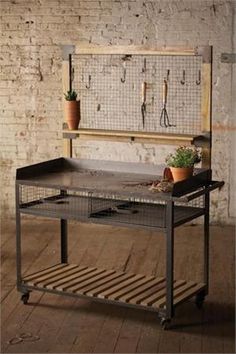 an old workbench with potted plants and tools hanging on the wall behind it