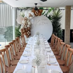 a long table is set up for a baby shower party with balloons and greenery