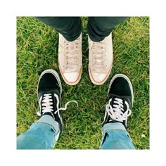 two people standing in the grass with their feet up and one person wearing white sneakers