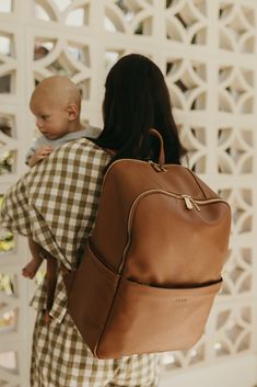 a woman with a baby in her back pack is looking at the white lattice wall