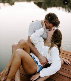 a man and woman sitting on a dock kissing