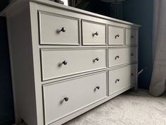 a large white dresser with drawers in a blue and gray room next to a window