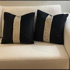 two black and gold pillows on a white couch