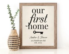 a wooden frame holding a sign that says our first home and a vase with a plant in it