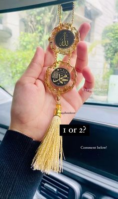 a person holding up a gold and black clock with tassels in their hand