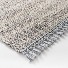 an area rug with fringes on the top and bottom, in light grey tones