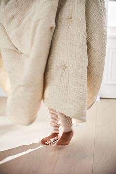 a person is standing on the floor with their feet propped up in bed linens