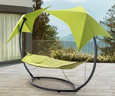 a swing chair with an umbrella attached to the top and bottom, sitting on a patio