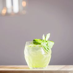 a green drink in a glass on top of a wooden table