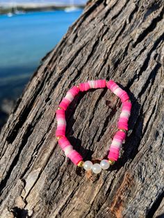 a pink and white beaded bracelet sitting on top of a tree