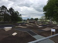 an empty skateboard park with ramps in the foreground and trees on the other side