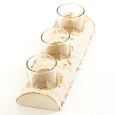 three shot glasses sitting on top of a piece of wood with some sand in them