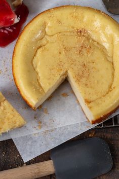 a cheesecake with one slice missing from it on top of wax paper next to a spatula