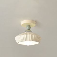 a white ceiling light mounted on the side of a wall in a room with gray walls