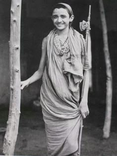 an old black and white photo of a woman holding a stick