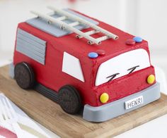 a cake shaped like a firetruck is on a wooden platter with utensils