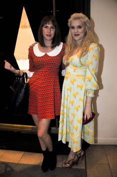 two women standing next to each other in front of a window