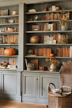 a room filled with lots of books on top of gray shelves next to a wicker chair