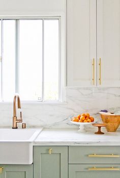 a kitchen with marble counter tops and white cabinets, along with brass pulls on the cabinet doors