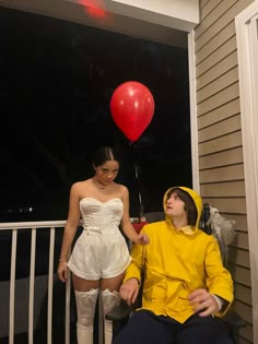 a man in a yellow raincoat sitting on a porch next to a woman with a red balloon