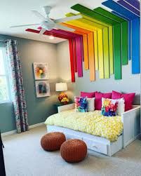 a bedroom decorated in rainbow colors with white bedding and colorful decor on the ceiling