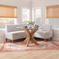 a living room area with a couch, table and rug on the hardwood flooring