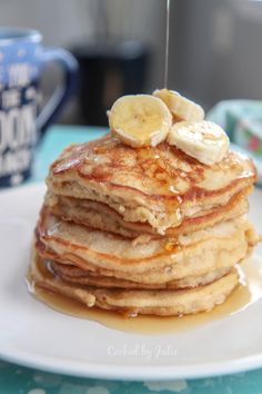 a stack of pancakes with syrup and bananas on top