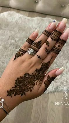 a woman's hand with henna tattoos on it and two rings in the middle