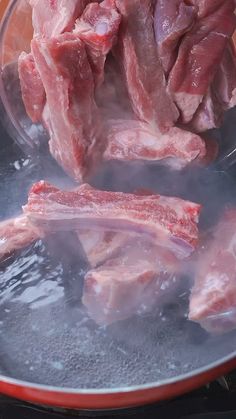 raw meat being cooked in a pan on the stove top with water and oil over it