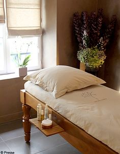 a bed with pillows and some candles on the end table in front of a window